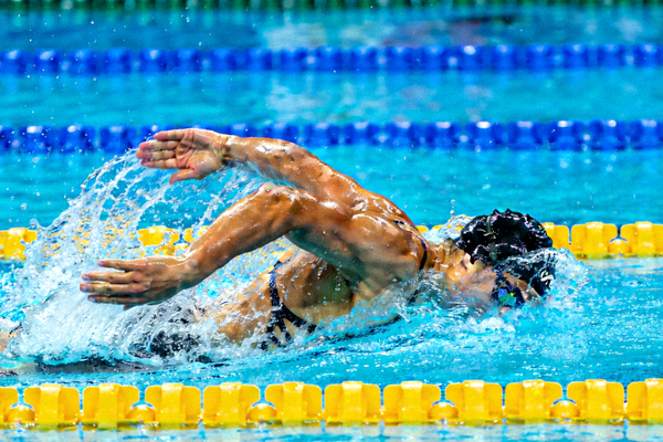 游泳运动员在泳道中奋力划水的竞技画面，水花四溅展现速度之美